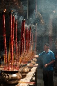 man putting incense in a pot