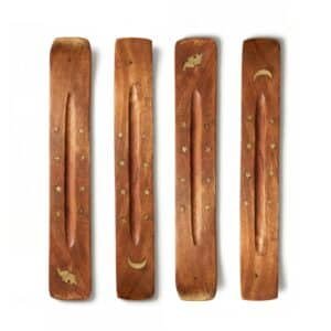 Dos porta inciensos de madera pulida en forma de canoa, uno decorado con una luna creciente y estrellas de latón, y el otro con un elefante y estrellas, sobre un fondo blanco puro.