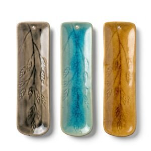 Tres porta sahumerios tipo canoa de cerámica esmaltada con diseño de espiga y efecto craquelado, colores gris, turquesa y ocre, medidas 22x6 cm.