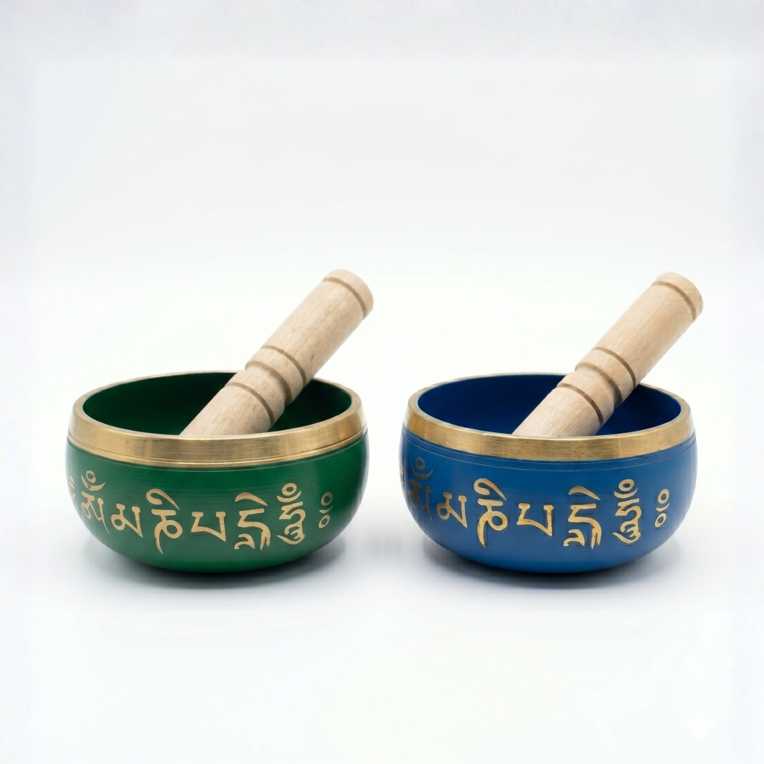 Dos cuencos tibetanos de meditación esmaltados en color verde esmeralda y azul mate, con el mantra Om Mani Padme Hum grabado en dorado y baquetas de madera.